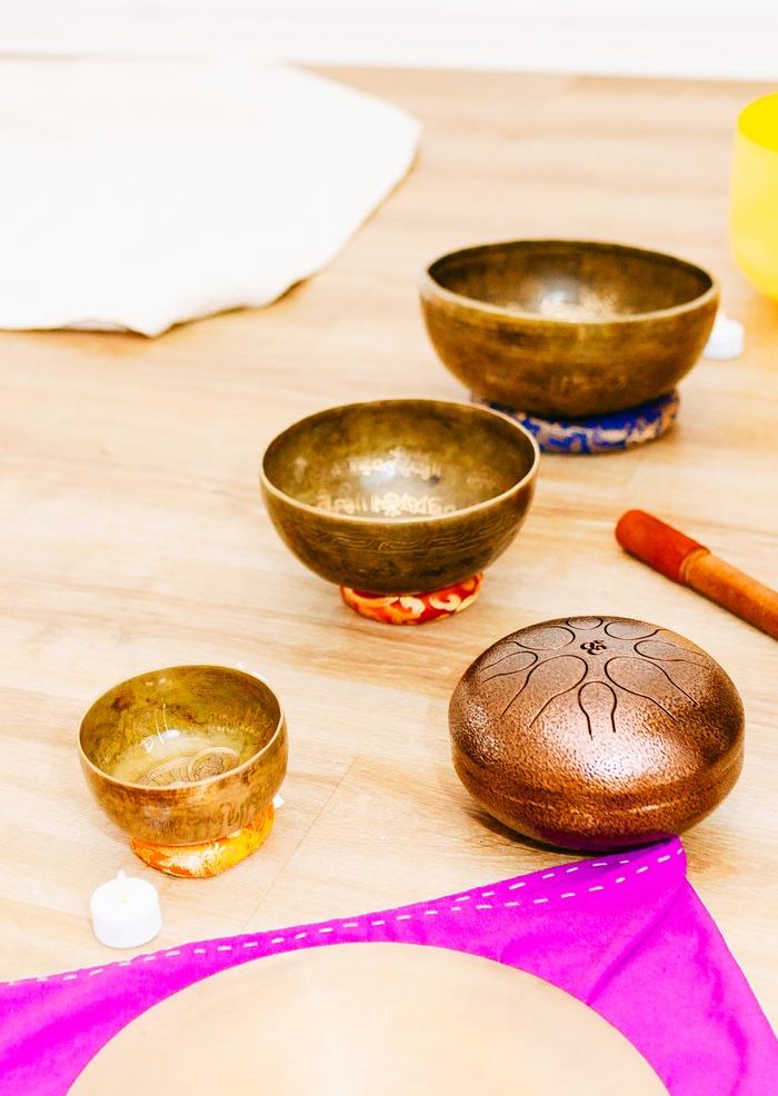 Home A serene arrangement of Tibetan singing bowls and mallet on a wooden floor for meditation.