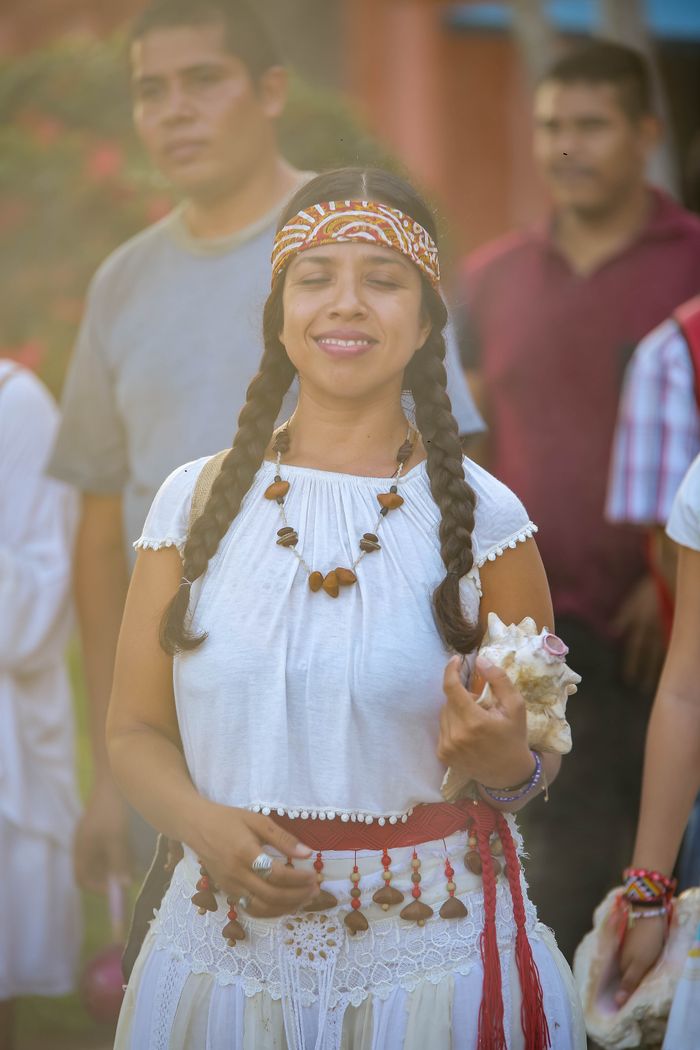 A woman in traditional attire joyfully participates in a festival parade outdoors.