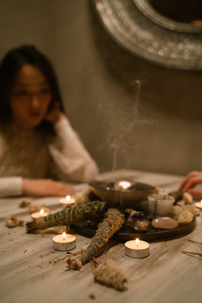 Home A serene indoor setting featuring burning candles and white sage, creating a calming atmosphere.